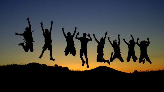 Symbolbild: Menschen springen vor Freude im Gegenlicht
