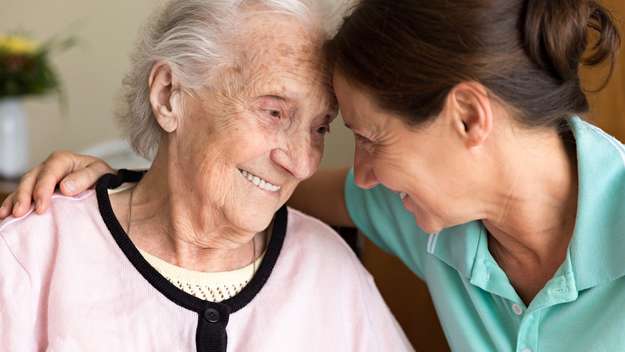 Eine Pflegerin nimmt eine alte Frau in den Arm