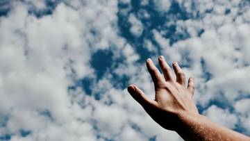Eine Hand streckt sich dem Himmel entgegen
