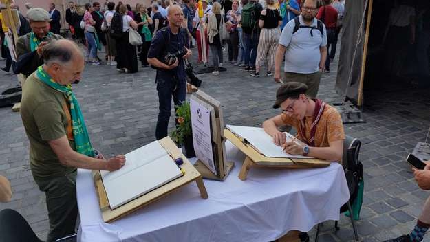 Zwei Männer schreiben Statements für die Klimabibel beim Kirchentag in Nürnberg