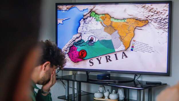 Ein Mann sitzt vor einem Computer. Auf dem Bildschirm ist eine Landkarte von Syrien zu sehen.