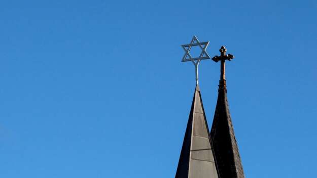 Türme einer Synagoge und einer Kirche vor blauem Himmel