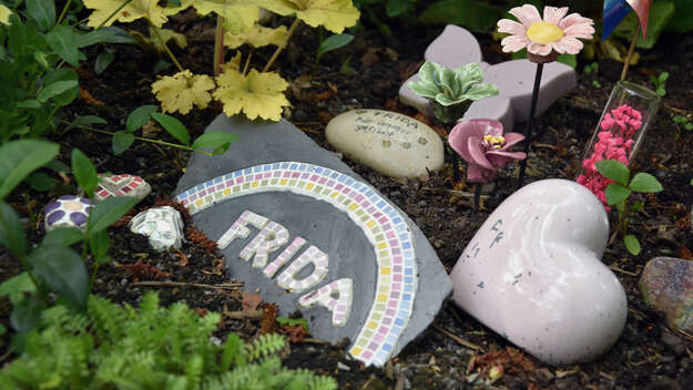 Grab auf einem Waldfriedhof in Bayern: Auf einem Stein steht als Mosaik der Name Frida.