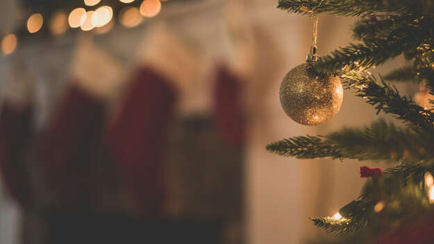 Ein Zweig eines Weihnachtsbaums mit einer goldenen Christbaumkugel