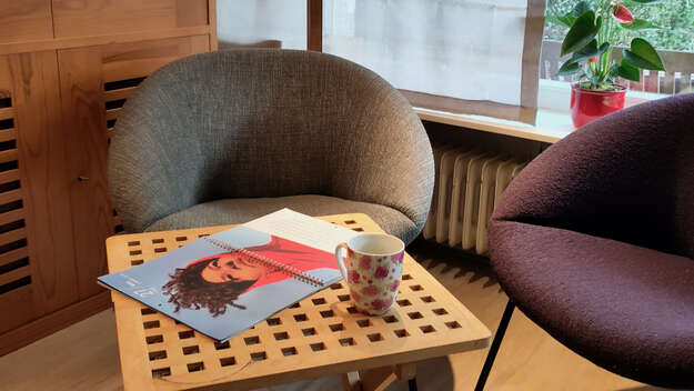 Auf einem kleinen Tisch liegt der Fastenkalender neben einer Kaffeetasse