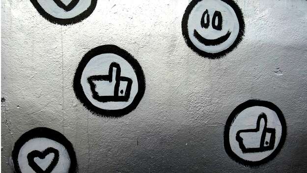 Wand mit einem Smiley, einem Herz und einem Daumen-hoch-Symbol