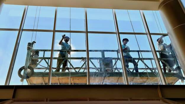 Fensterputzer durch das Fenster eines Bürohauses betrachtet