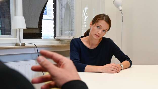 Vertrauliche Beratungssituation: Eine Frau sitzt an einem Tisch und hört aufmerksam zu