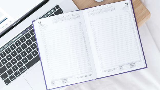Ein Taschenkalender liegt quer über einem Laptop