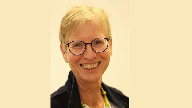 Martina Jakubek, Vorsitzende der EAfA, blickt laechelnd in die Kamera. Sie traegt blonde, kurze Haare und eine Brille