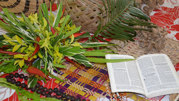 Symbolbild: Matte mit Palmwedeln und Bibel
