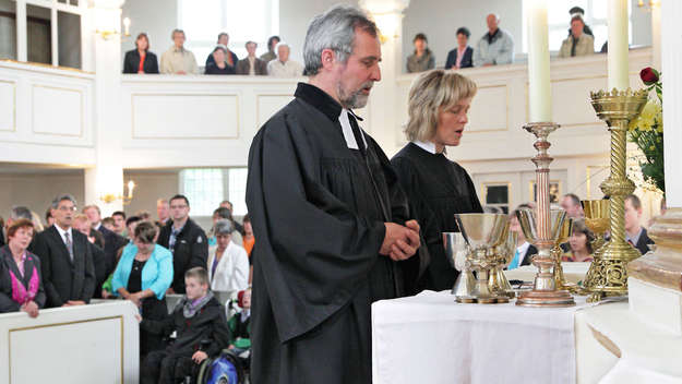 Pfarrerin und Pfarrer zelebrieren am Altar