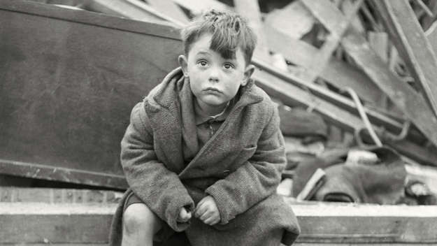 Ein kleiner Junge sitzt fragend in Trümmern