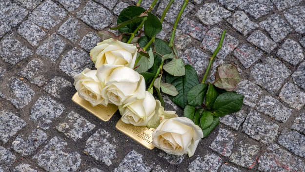 'Stolpersteine' bedeckt mit gelben Rosen