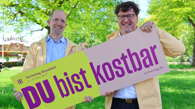 Präses Latzel und Kirchentagspräsident Torsten Zugehör präsentieren das Motto des Kirchentags 'DU bist kostbar'