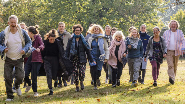 Symbolbild - eine Menschengruppe läuft über eine grüne Wiese