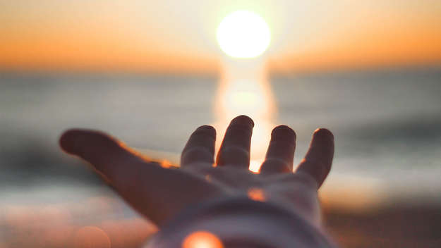 Symbolbild - Hand hält Sonne - Gott hält die ganze Welt