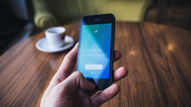 Eine Hand hält ein Smartphone mit dem Twitter-Anmelde-Bildschirm in der Hand.