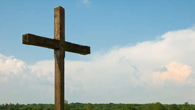 Kreuz aus Holz vor blauem Himmel.