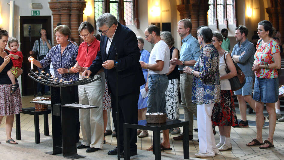 Gottesdienstbesucher zünden Kerzen an