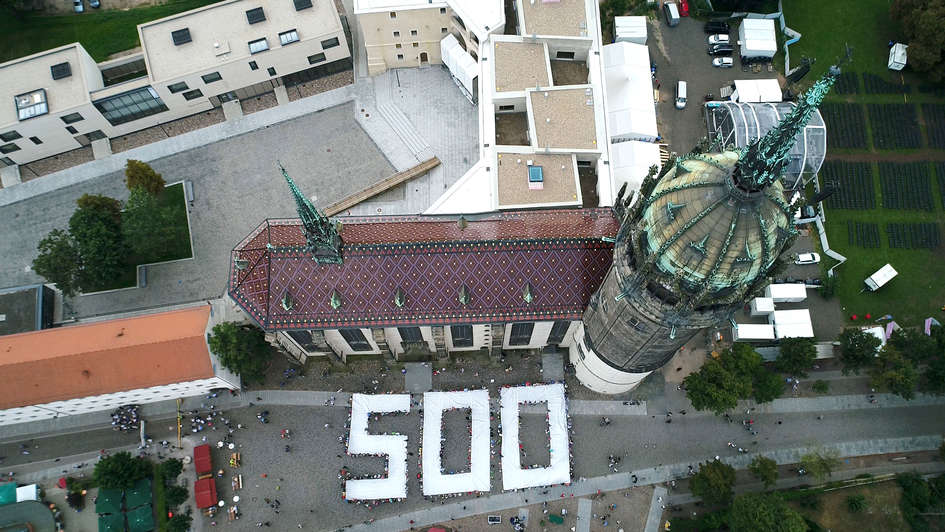 Menschen halten eine 500 vor der Schlosskirche in Wittenberg Menschen halten eine 500 vor der Schlosskirche in Wittenberg