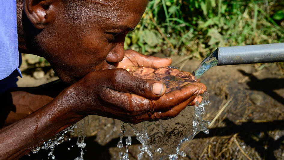 Mann trinkt Wasser an einem Brunnen in Kenia