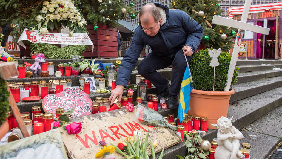 Pfarrer Martin Germer zwischen Trauerkerzen, Blumen und Kreuzen