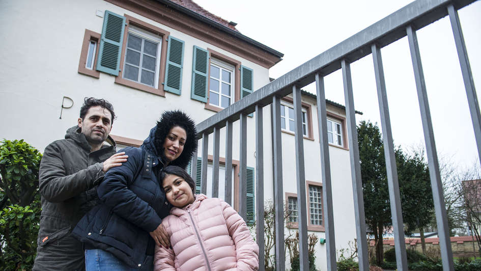 Flüchtlingsfamilie vor einer Kirche