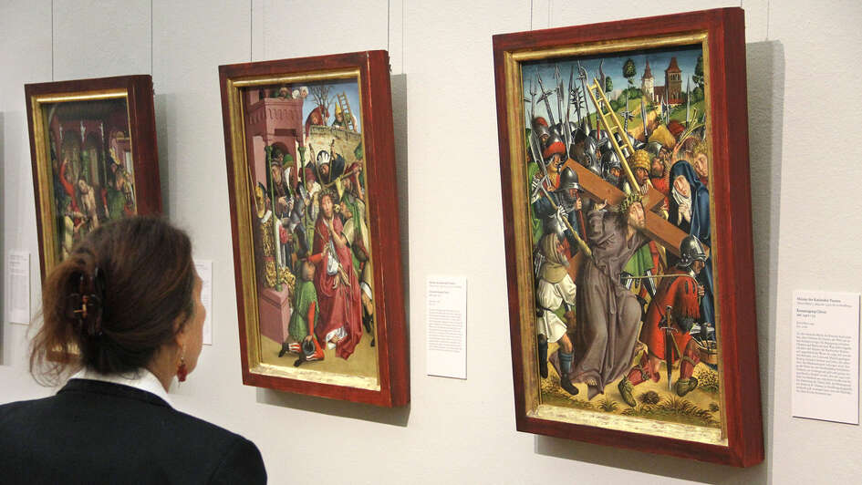 Frau schaut sich in einer Ausstellung Bilder zur Passion an Frau schaut sich in einer Ausstellung Bilder zur Passion an