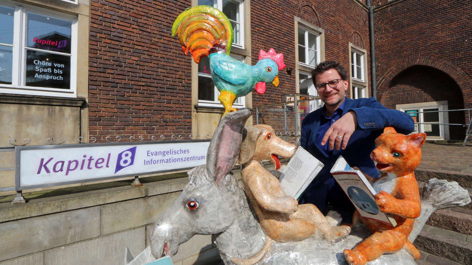 Pastor Hans-Jürgen Jung mit einerbunten Skulptur der Bremer Stadtmusikanten vor dem Evangelichen Informationszentrum 'Kapitel 8' in Bremen