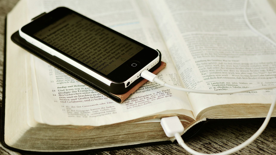 Smartphone liegt auf aufgeschlagener Bibel