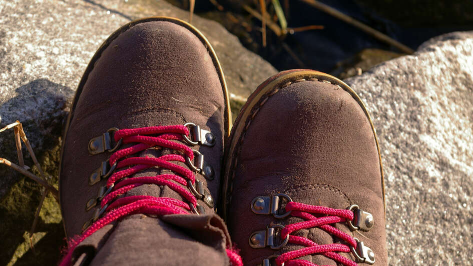 Zwei Wanderschuhe mit roten Schnürsenkeln ragen ins Bild
