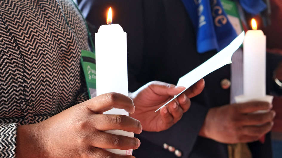 Vertreter des Weltkirchenrats halten eine Kerze