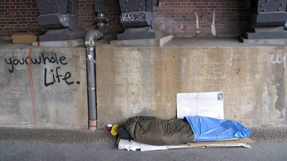 Ein Obdachloser liegt, in einen Schlafsack eingerollt, unter der Bahnbrücke in der Luisenstrasse in Berlin.