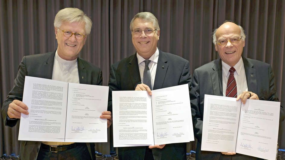 Heinrich Bedford-Strohm, Christian Schad, Gerhard Ulrich mit unterzeichneten Verträgen zum Verbindungsmodell