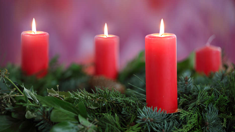 Adventskranz mit drei brennenden roten Kerzen