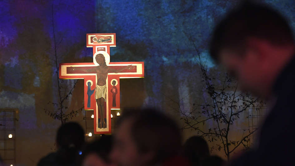 Betende vor dem erleuchteten Taizé-Kreuz