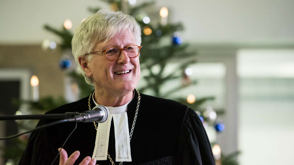 EKD-Ratsvorsitzender Heinrich Bedford-Strohm im Talar vor einem geschmückten Tannenbaum