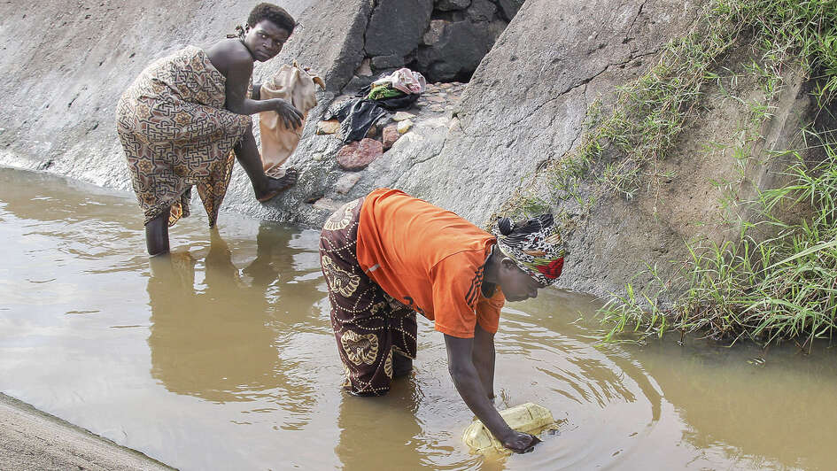 Frauen schöpfen Wasser in einem Graben in Burundi Frauen schöpfen Wasser in einem Graben in Burundi