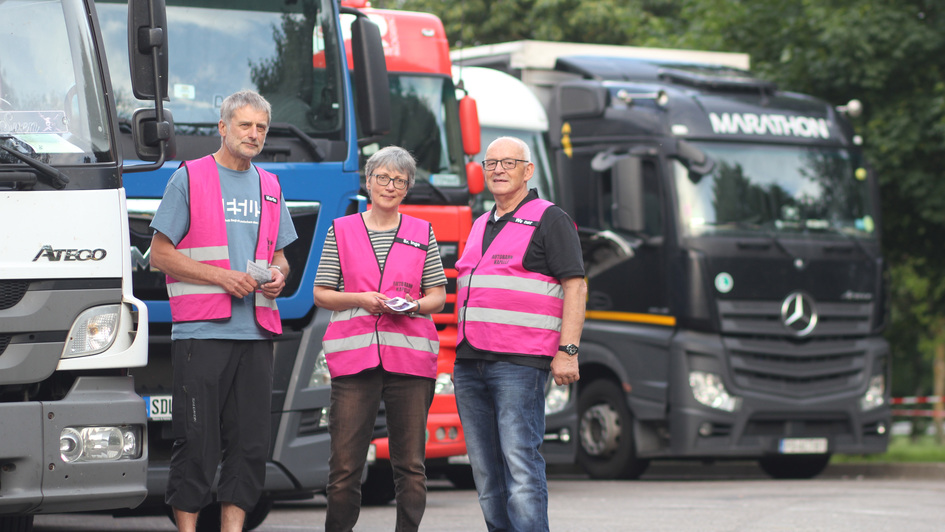 Martin Heubach, Schwester Inge vom Hergershof und Werner Kretzschmar in pinken Warnwesten vor einer Reihe LKW
