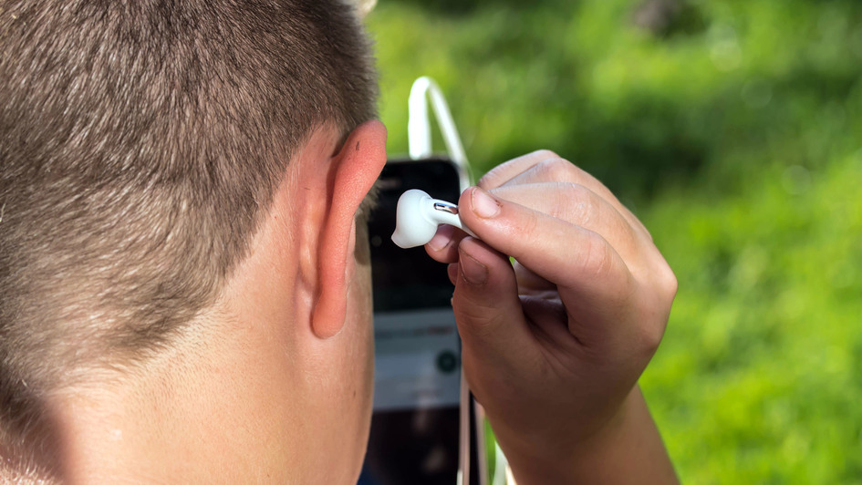 Ein junger Mann nimmt einen Kopfhörer aus dem, Ohr