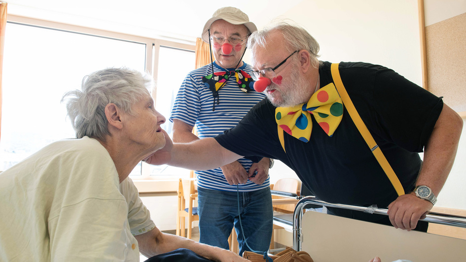 Die ehrenamtlichen Klinik-Clowns Hans Jürgen Becker und Peter Fröhlich tragen bunte Fliegen, wenn sie eine  Patientin besuchen