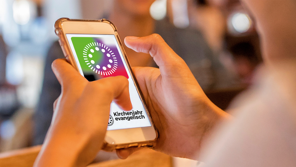 Symbolbild zur Kirchenjahr-App, Hände halten ein Smartphone auf dem der Startbildschirm kirchenjahr-evangelisch zu sehen ist Symbolbild zur Kirchenjahr-App, Hände halten ein Smartphone auf dem der Startbildschirm kirchenjahr-evangelisch zu sehen ist