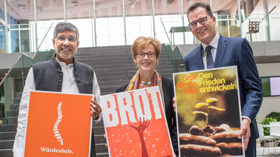Der indische Friedensnobelpreisträger Kailash Satyarthi, Cornelia Füllkrug-Weitzel, Präsidentin von 'Brot fuer die Welt' und Bundesentwicklungsminister Gerd Müller (CSU) mit Plakaten von 'brot für die Welt'
