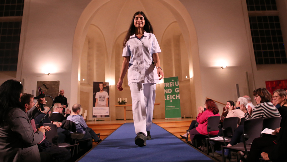 Modenschau beim Start der Menschenrechtskampagne zu fairer und gerechter Kleidung: Ein Model läuft in weißer Kleidung über einen Lauftsteg Modenschau beim Start der Menschenrechtskampagne zu fairer und gerechter Kleidung: Ein Model läuft in weißer Kleidung über einen Lauftsteg