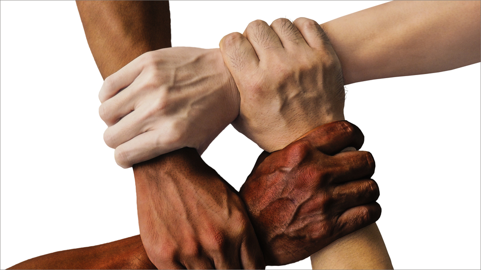 Hände unterschiedlicher Hautfarben halten einander