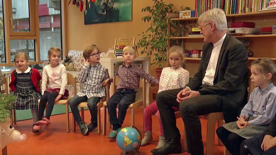 Der EKD-Ratsvorsitzende Heinrich Bedford-Strohm sitzt in einem Stuhlkreis unter Kindern in einer Kita