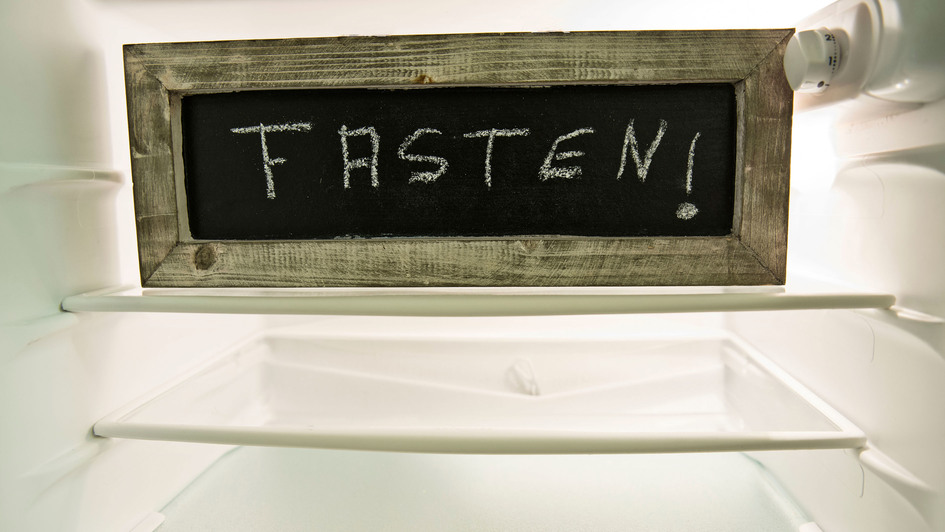 Tafel mit der Aufschrift „Fasten“ in einem leeren Kühlschrank