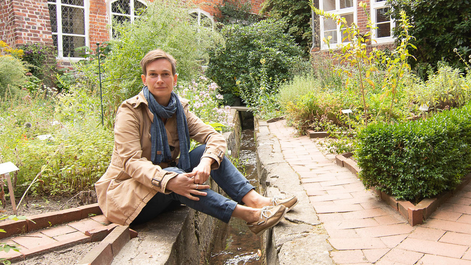 Carolin George sitzt im Kräutergarten des evangelischen Frauenklosters Lüne bei Lüneburg