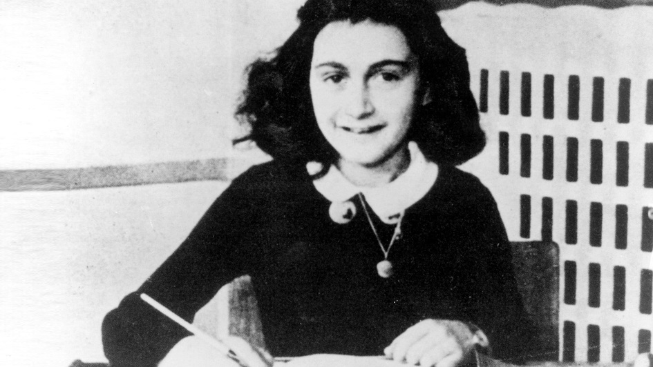Anne Frank, am Tisch sitzend, schreibt in ein Buch. Portrait ca. 1942